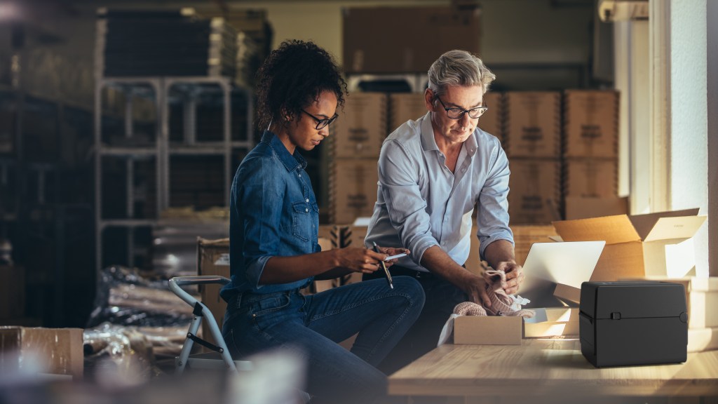 Мъж и жена опаковат пакети в склад - употреба на настолни баркод принтери Toshiba серия BV400D в логистиката