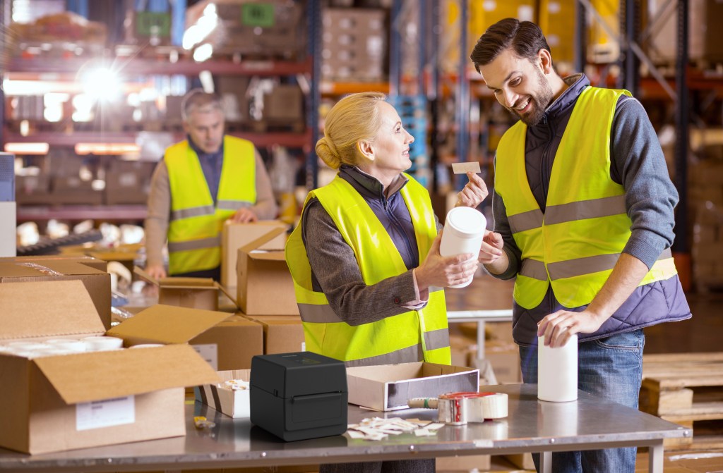 Работници в склад облепят продукти с етикети - употреба на настолни баркод принтери Toshiba серия BV400D в производството